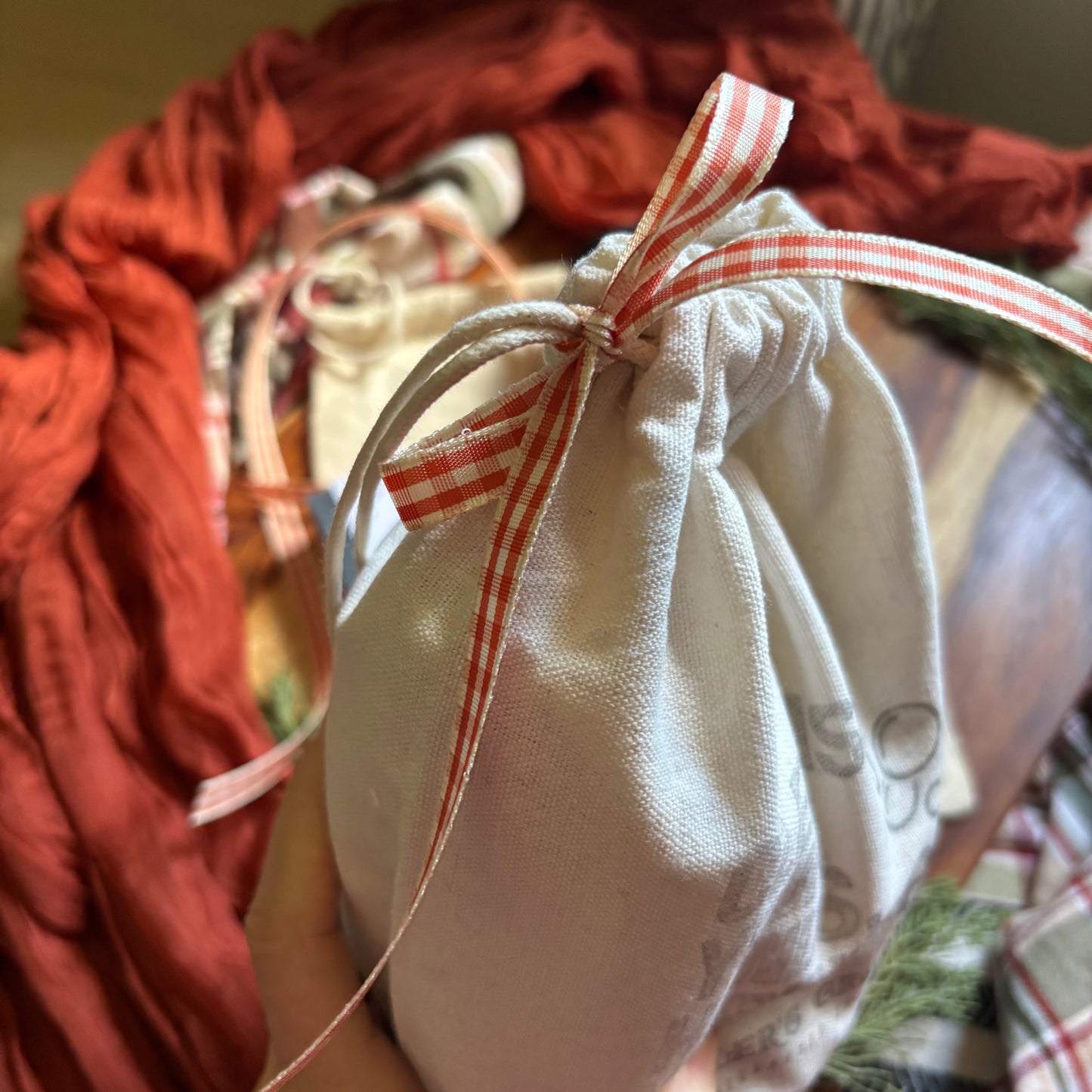 White drawstring bag with a red and white checkered ribbon on a blurred background