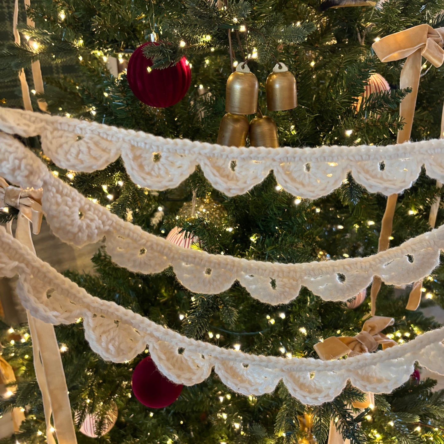 Decorative lace garland in front of a Christmas tree with ornaments.