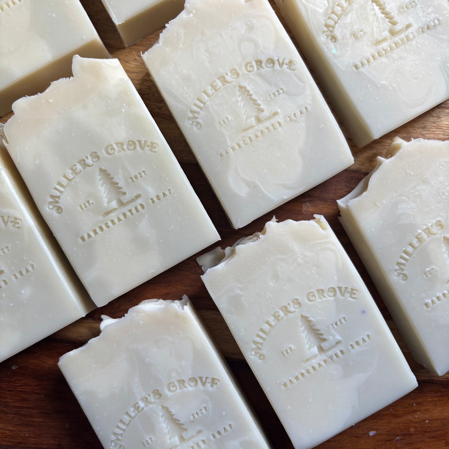 Multiple bars of soap with 'Miller's Grove' branding on a wooden surface.