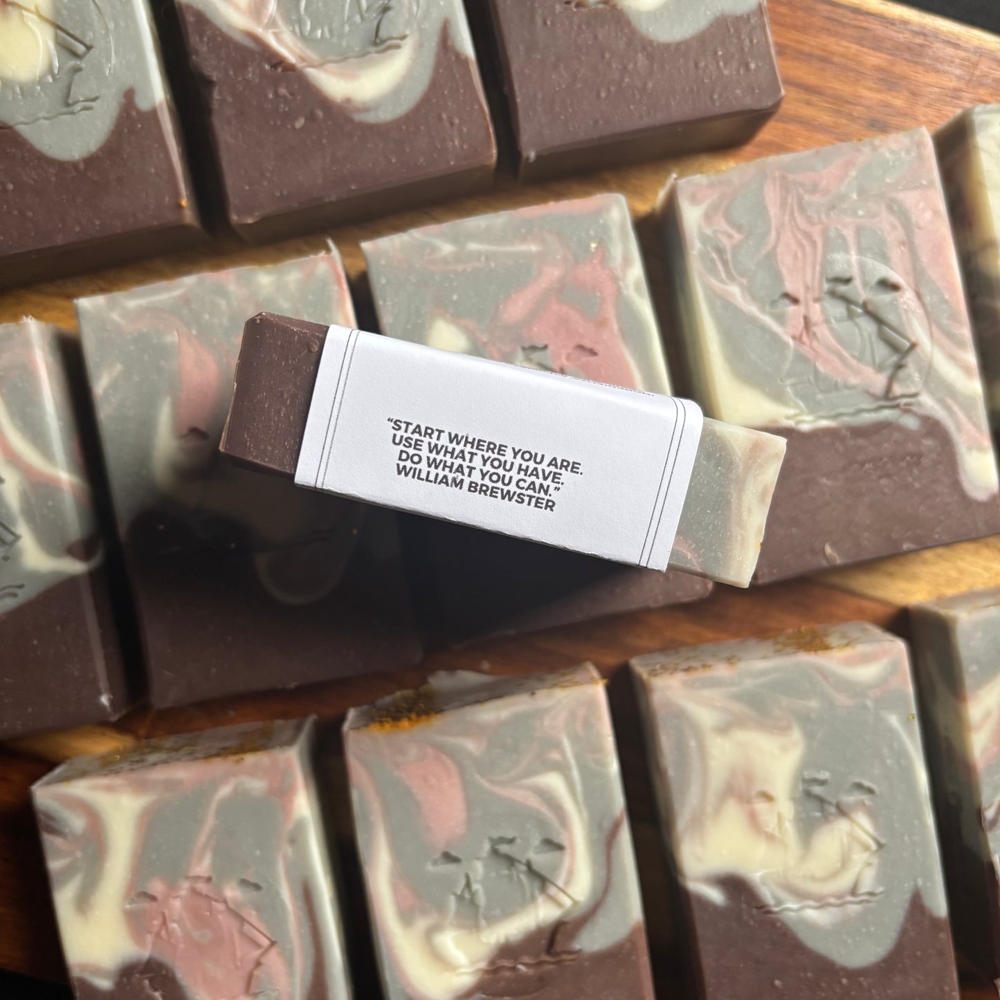 Marbled soap bars with a motivational quote label on a wooden surface