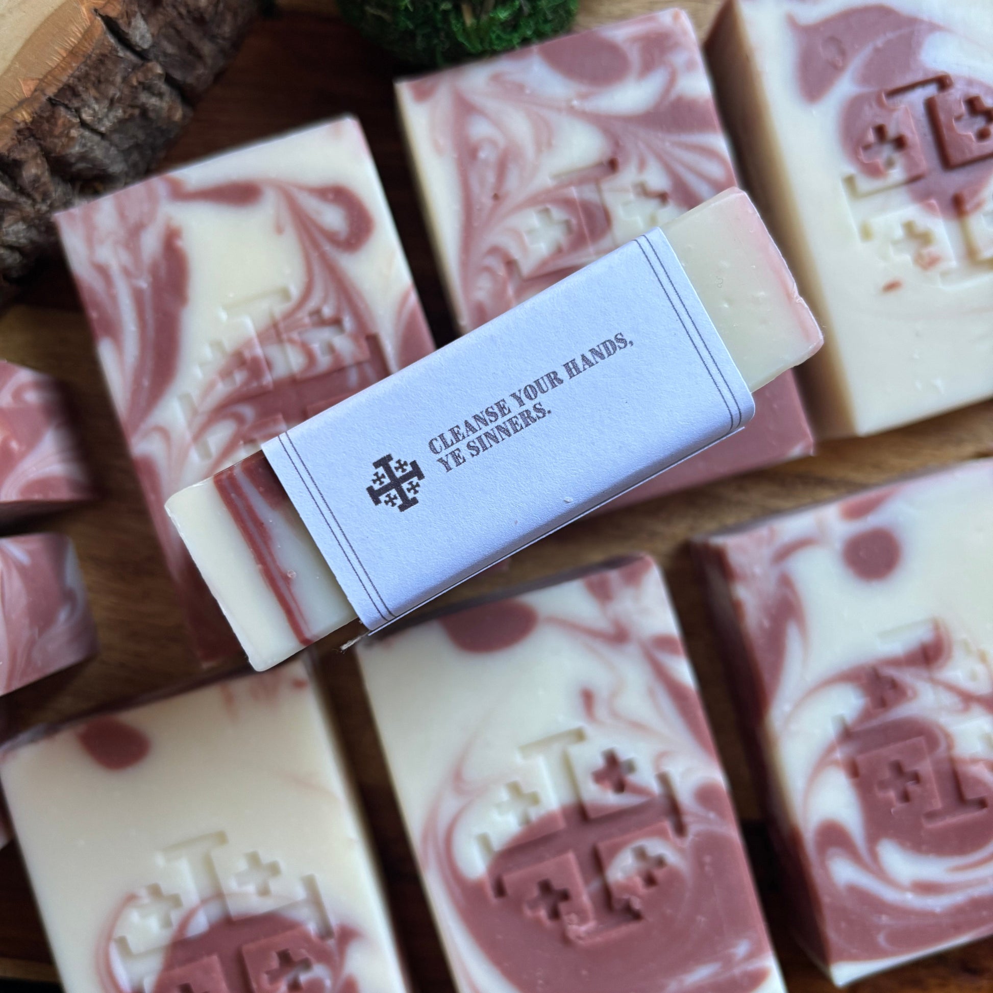 Handmade soap bars with a marbled design and a visible brand label on a wooden surface.