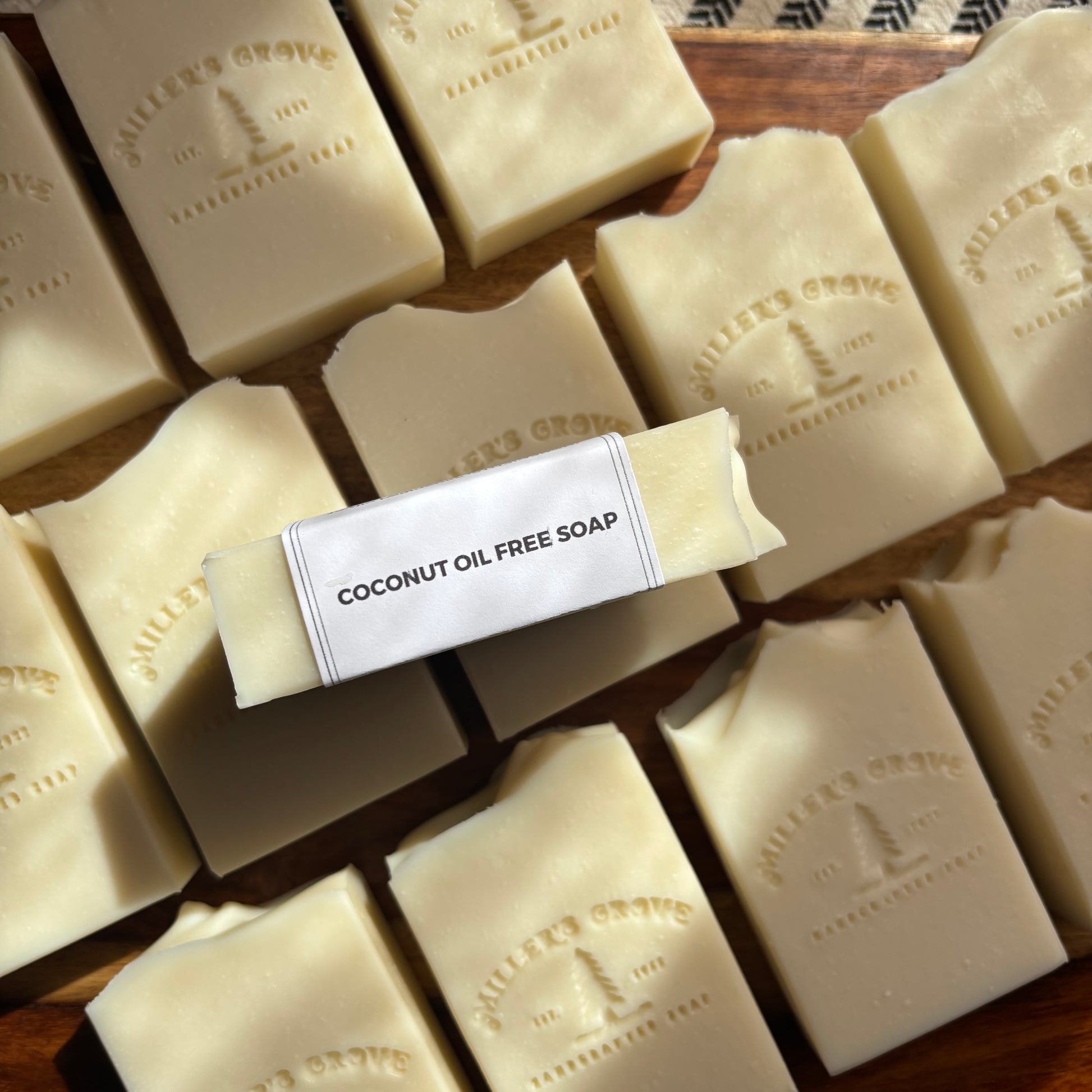 Multiple bars of coconut oil free soap on a wooden surface with a label in the center.