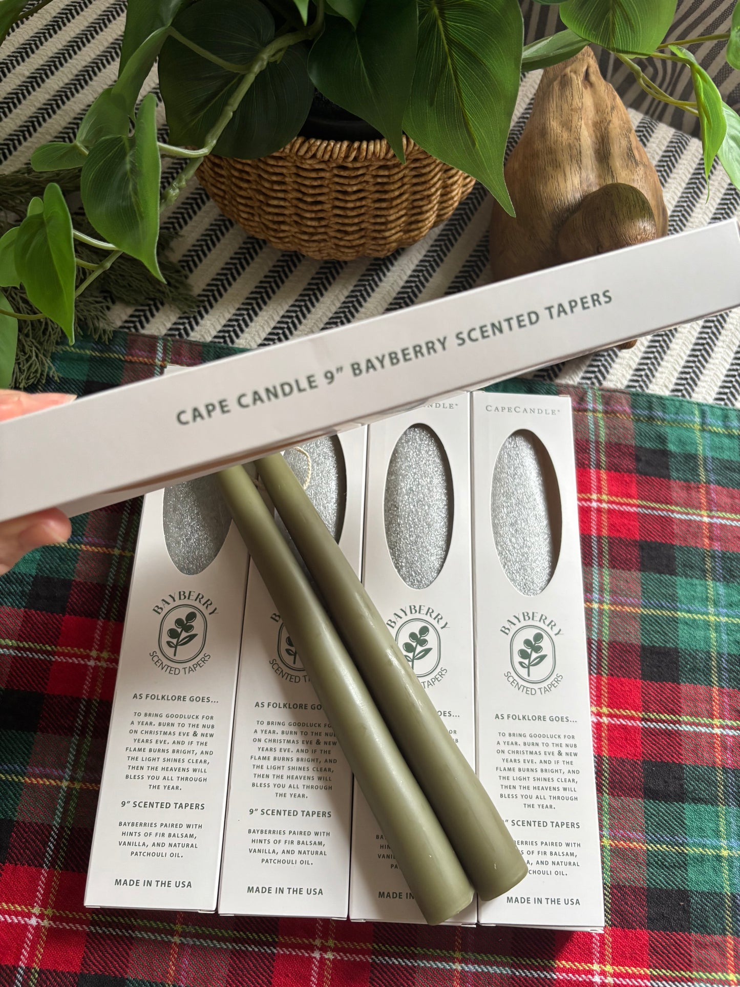Candle tapers and packaging on a plaid fabric background