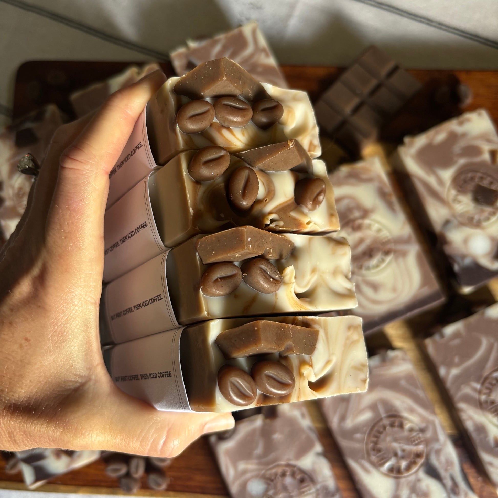 Hand holding a stack of coffee-flavored soap bars with visible coffee beans.