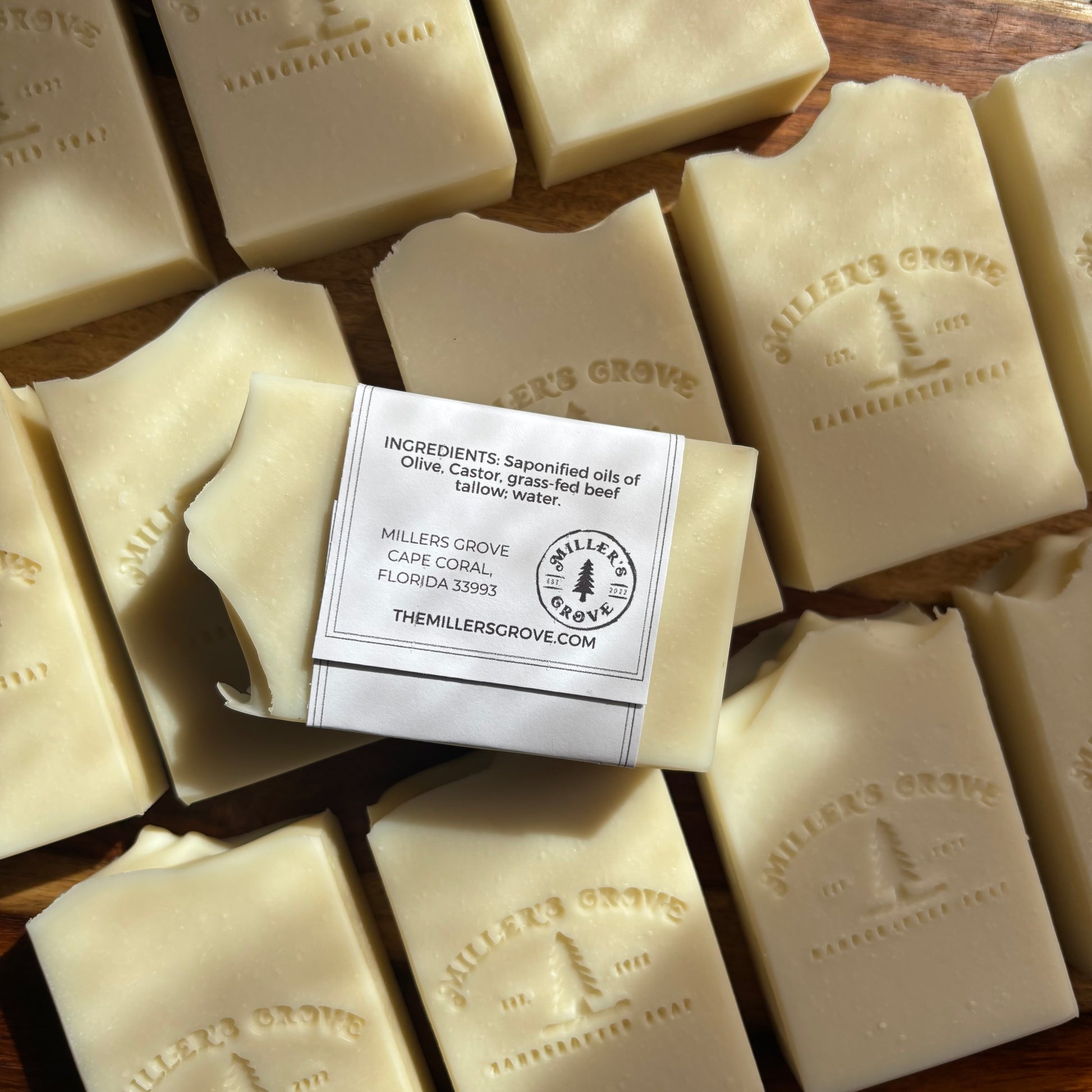Multiple bars of Miller's Grove soap with a single bar on a label, displayed on a wooden surface.