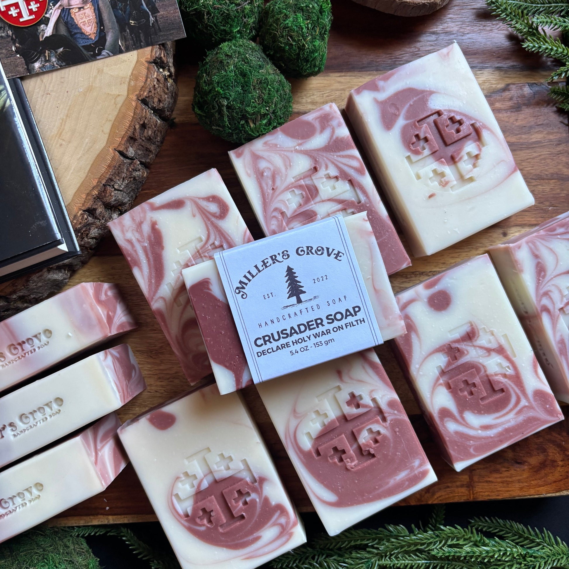 Handmade soap bars with a brand label on a wooden board with greenery