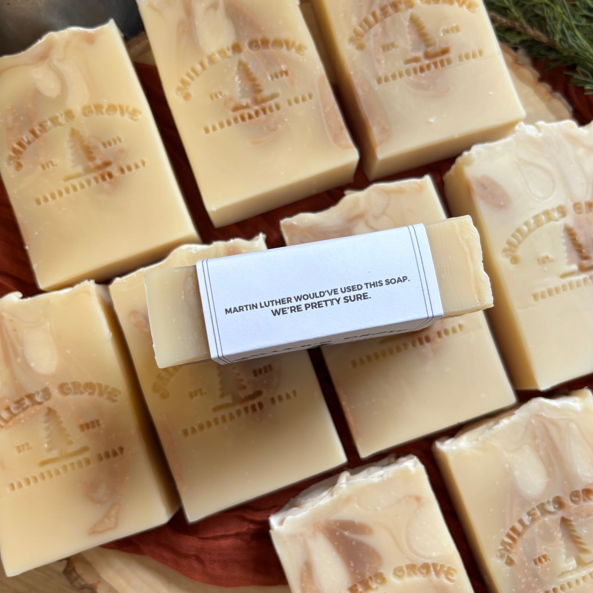 Bar of soap with a humorous label surrounded by other soap bars on a wooden surface