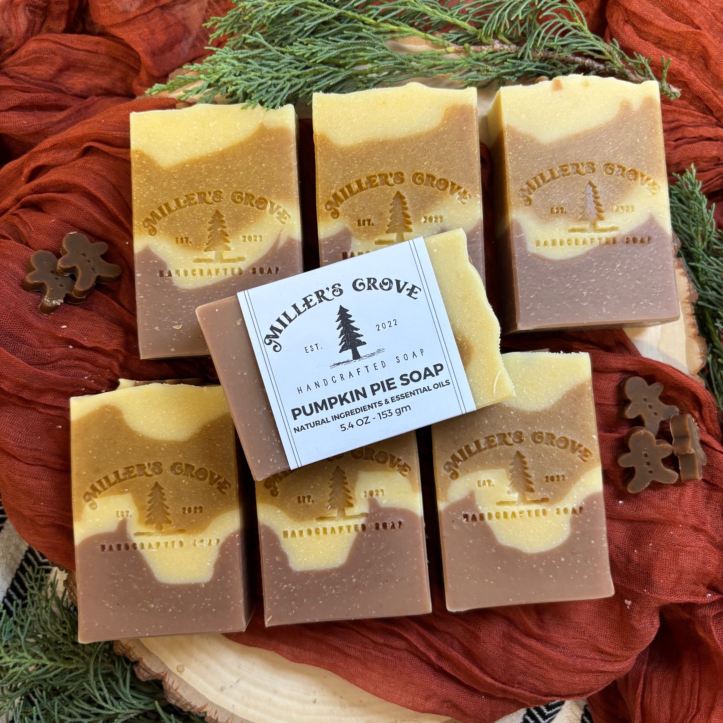 Miller's Grove soap bars with a focus on pumpkin pie soap on a rustic wooden surface with greenery.