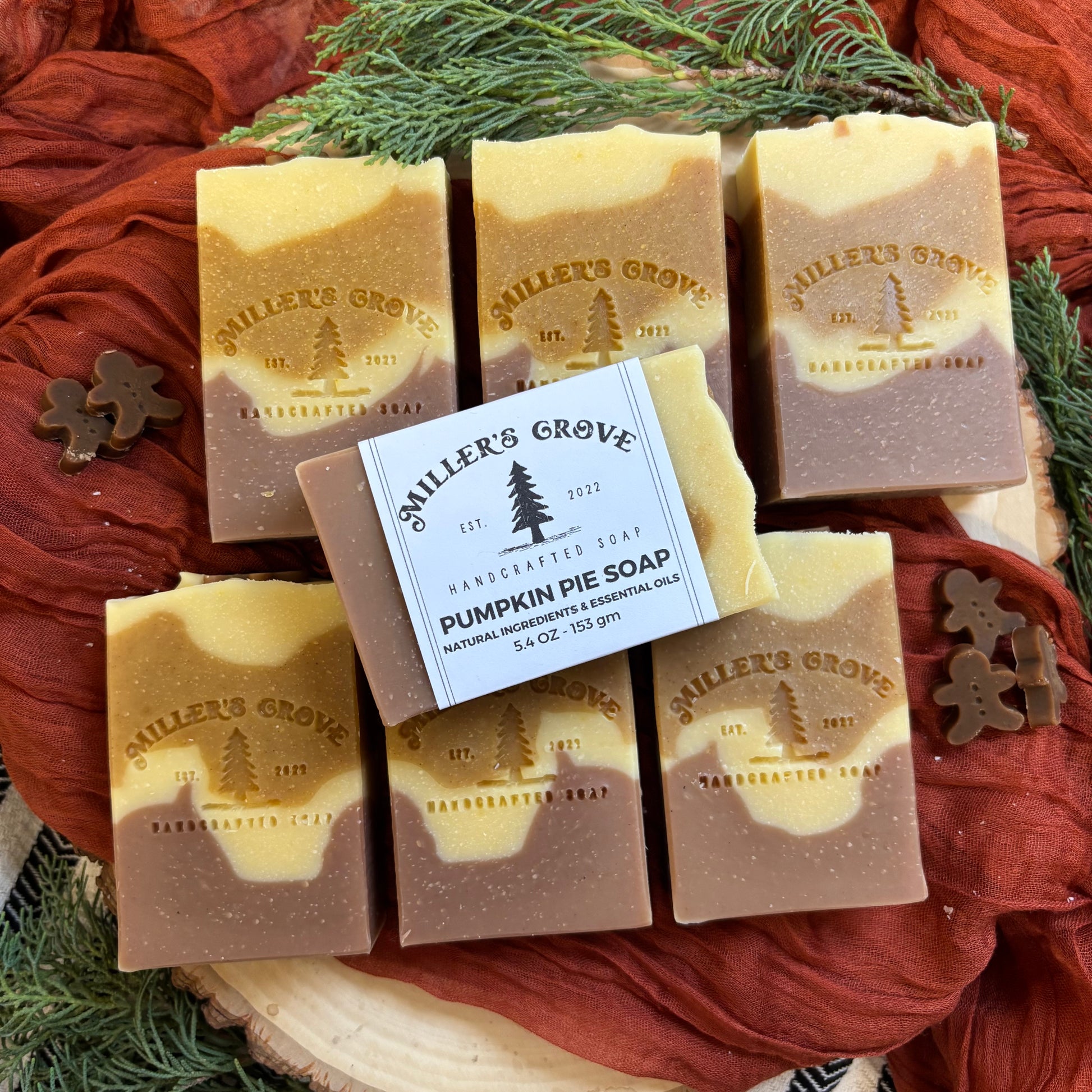 Miller's Grove soap bars with a focus on pumpkin pie soap on a rustic wooden surface with greenery.