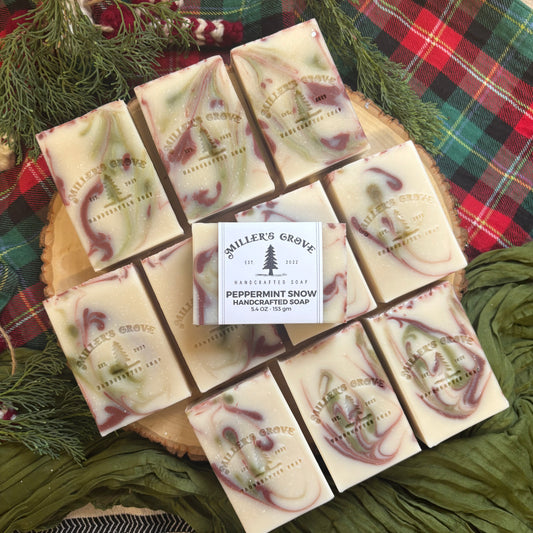 Handcrafted soap bars with a 'Miller's Grove' label on a wooden board with a plaid fabric background.
