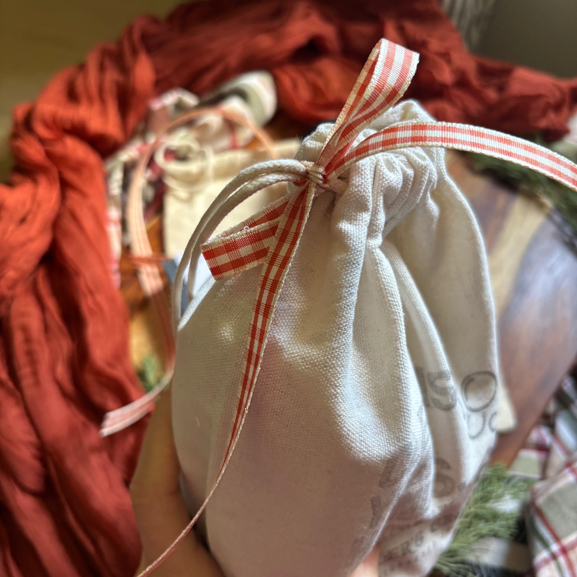 White drawstring bag with a red and white checkered ribbon on a blurred background