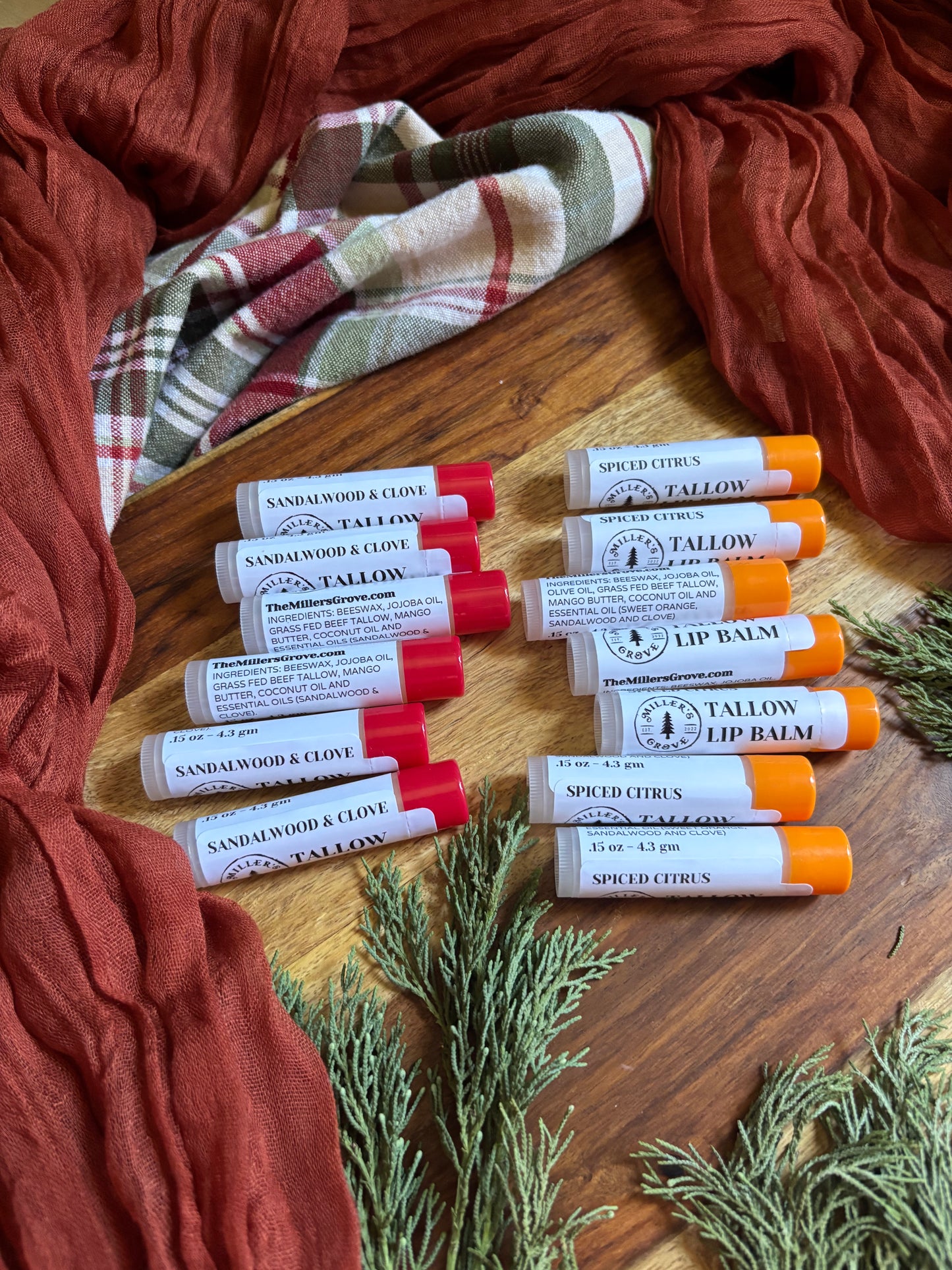 Lip balm tubes on a wooden surface with a plaid cloth and red fabric in the background.