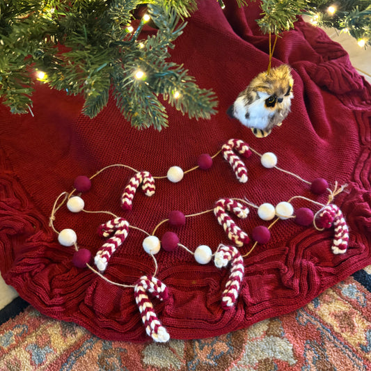 Red textured surface with Christmas decorations including candy canes and a small animal figurine.