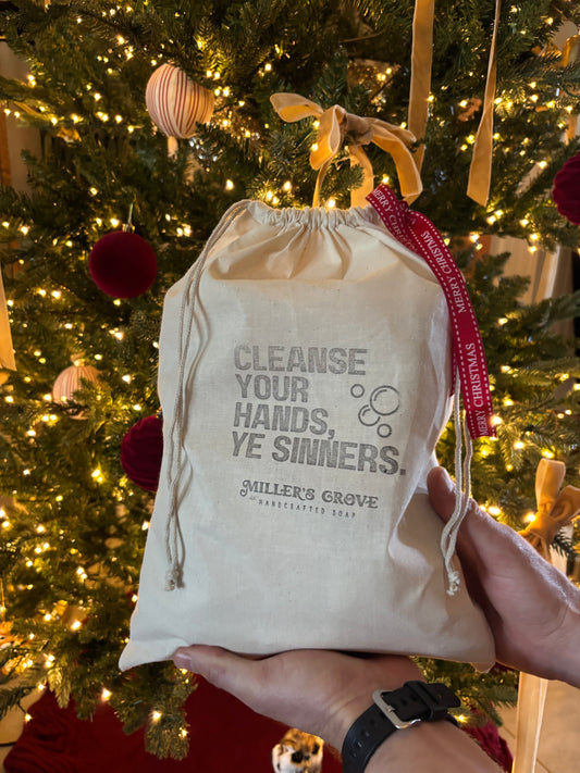 Drawstring bag with text held in front of a decorated Christmas tree