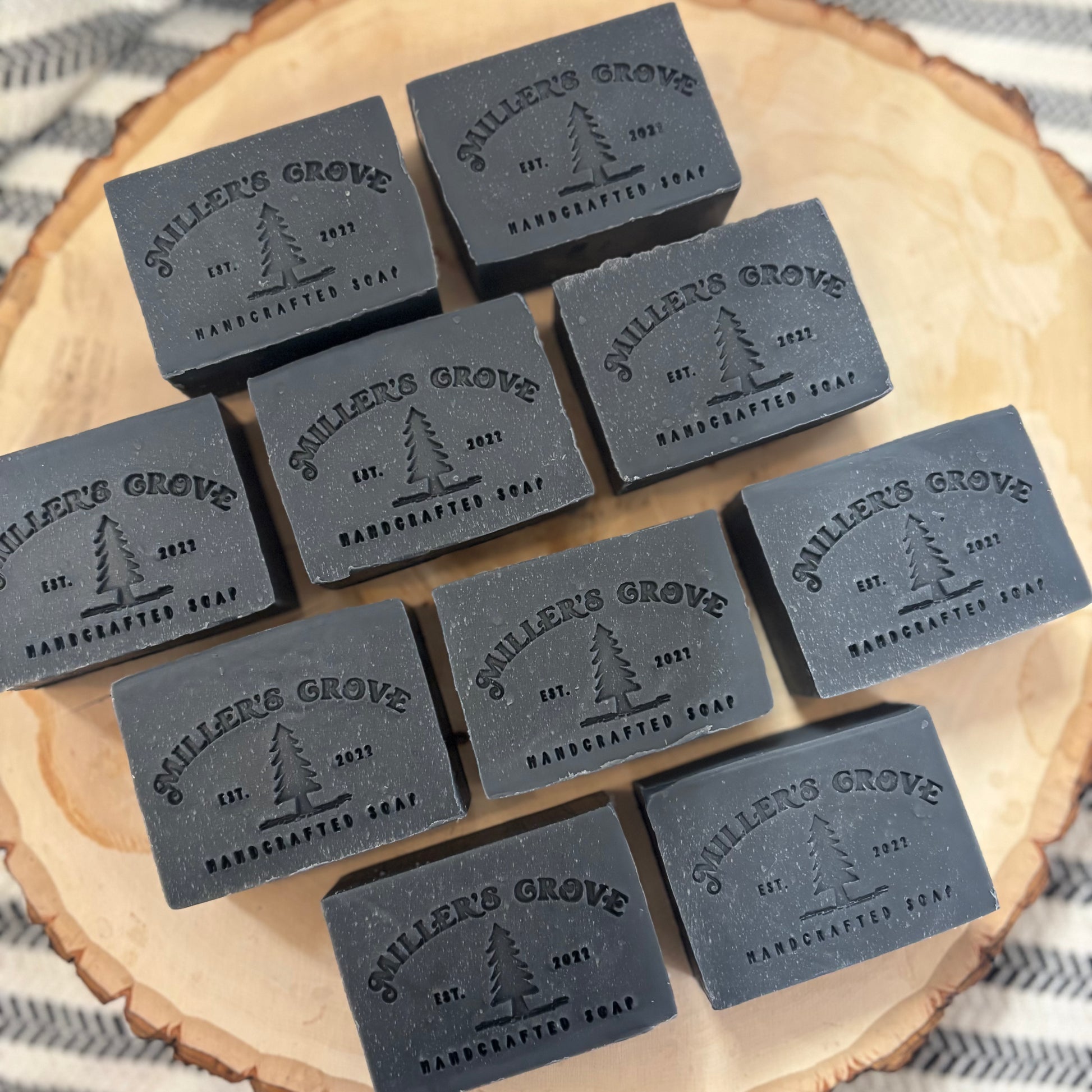 Multiple bars of 'Miller's Grove' handcrafted soap on a wooden surface.