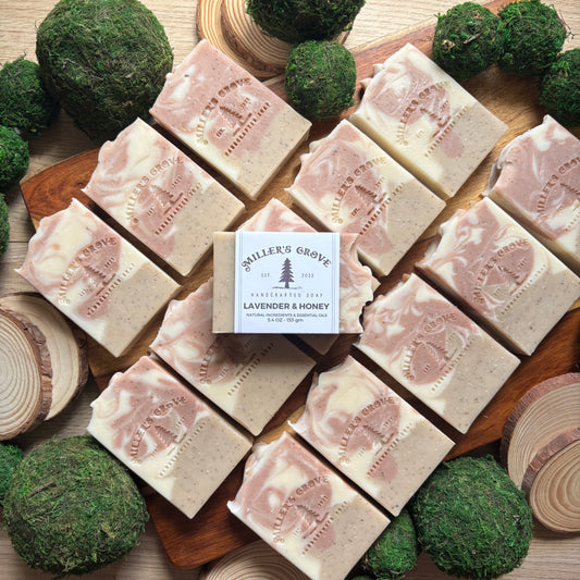 Multiple bars of soap with a box labeled 'Miller's Grove' on a wooden surface with green decorative elements.