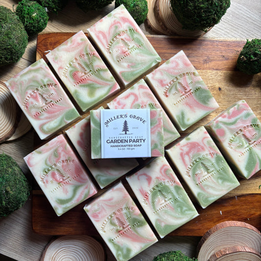 Handcrafted soap bars with a 'Miller's Grove' label on a wooden surface with greenery.