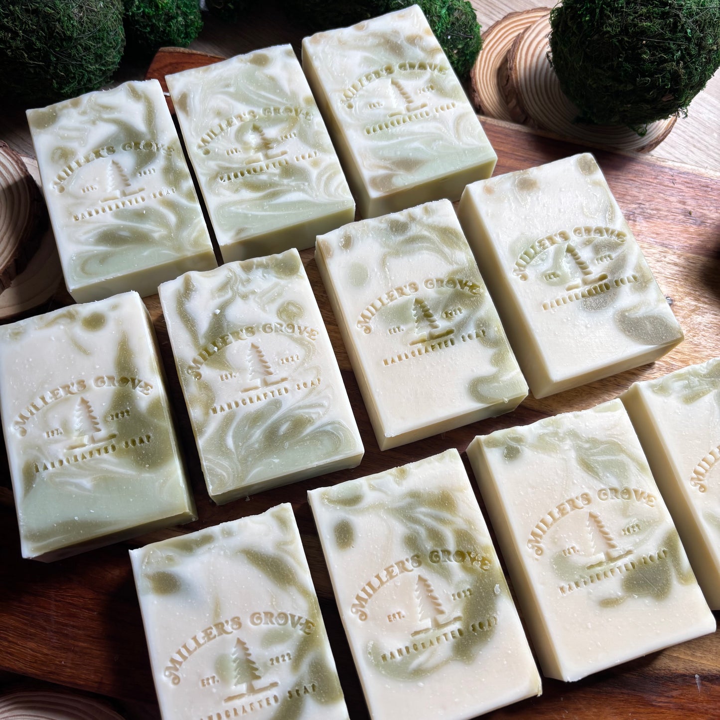Multiple bars of soap with 'Miller's Grove' branding on a wooden surface.