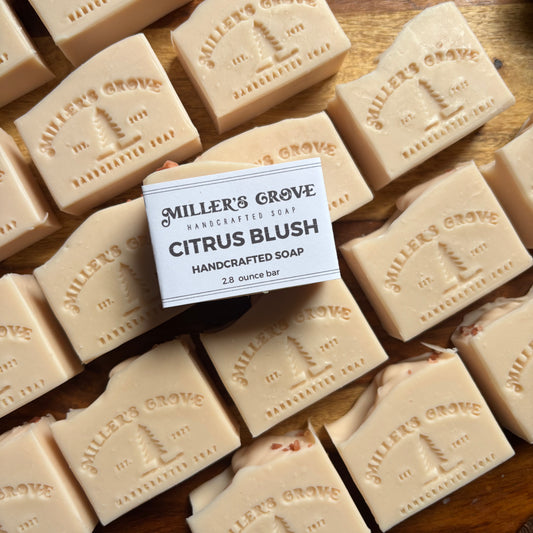 Multiple bars of Miller's Grove Citrus Blush soap on a wooden surface with a label in the center.