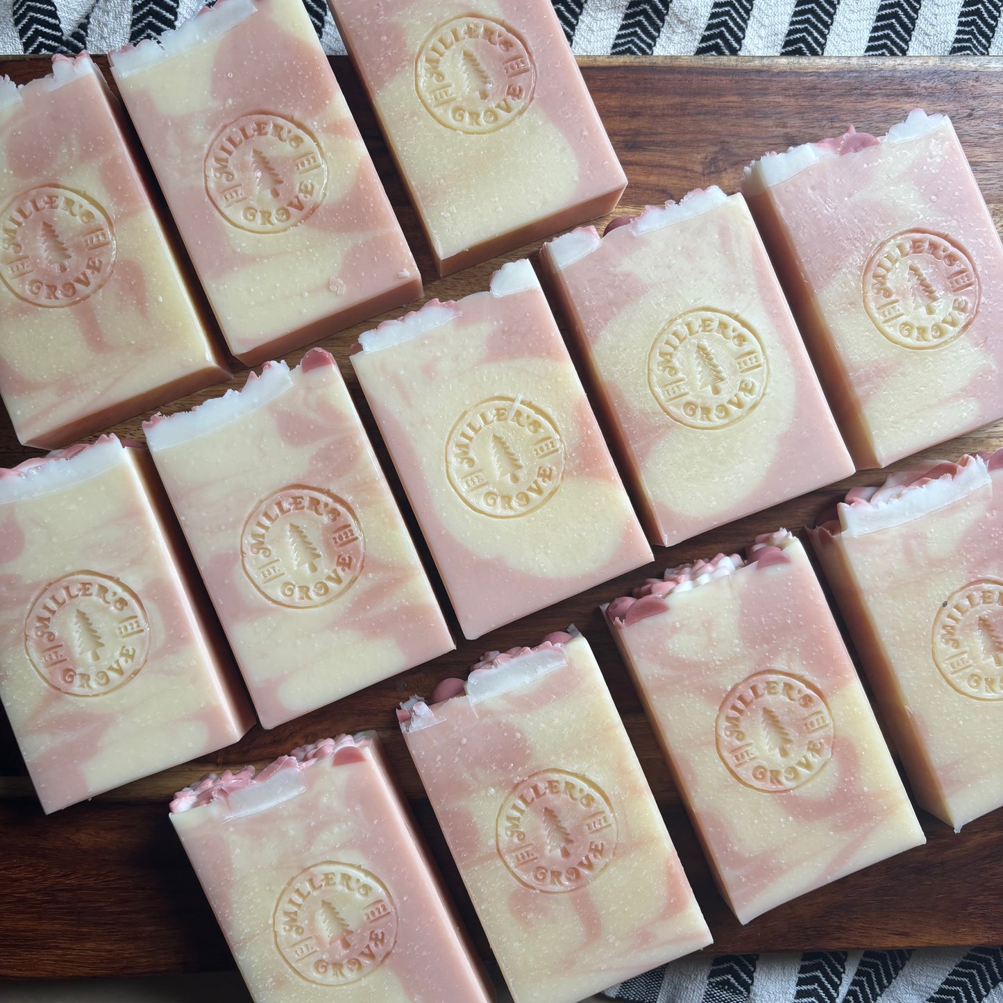 Row of pink soap bars with a visible brand logo on a wooden surface.