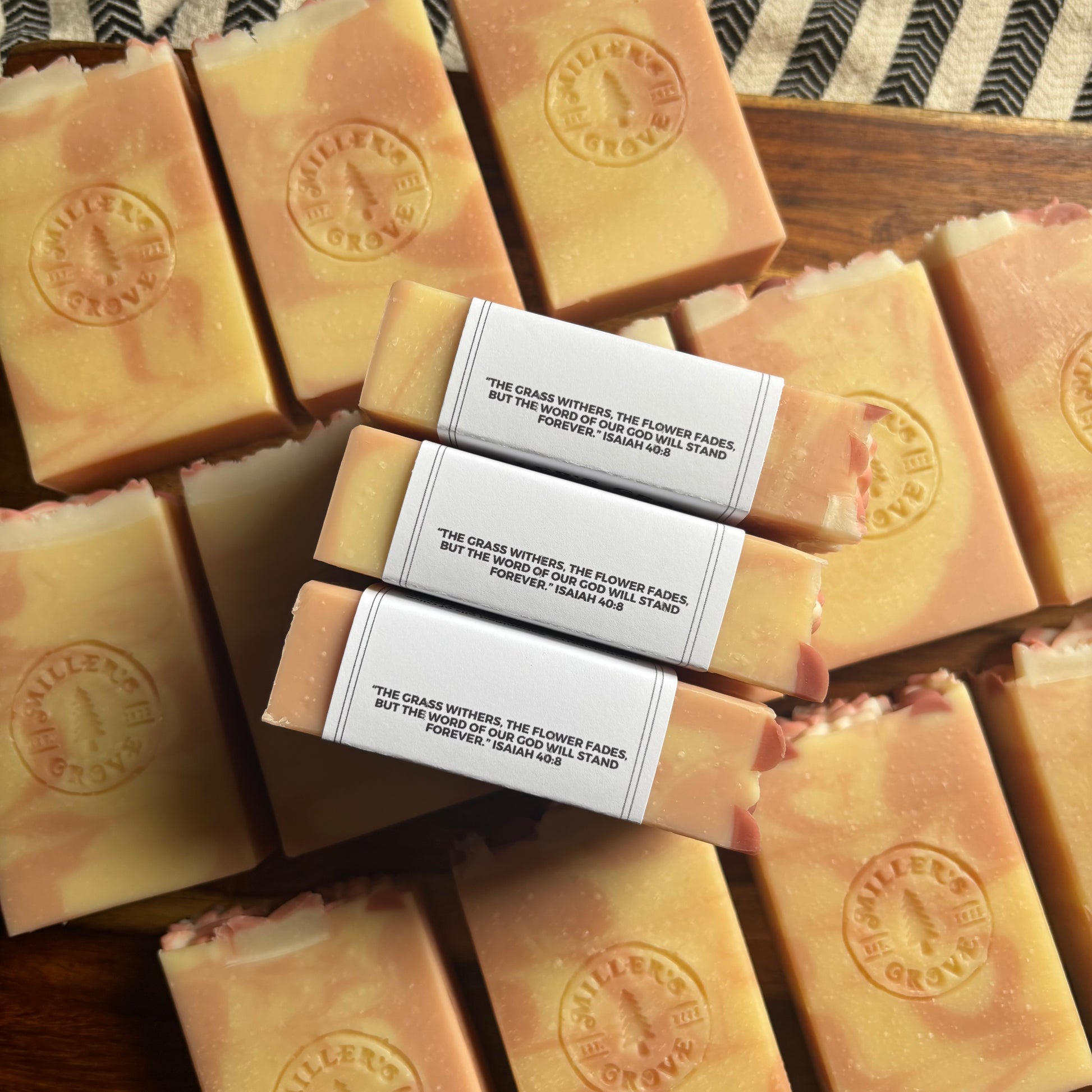 Bars of soap with visible branding and a quote on a wooden surface