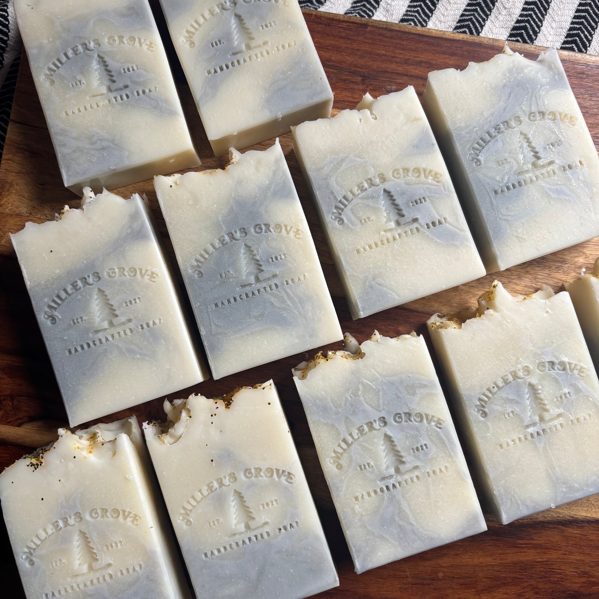 Multiple bars of soap with 'Miller's Grove' branding on a wooden surface.