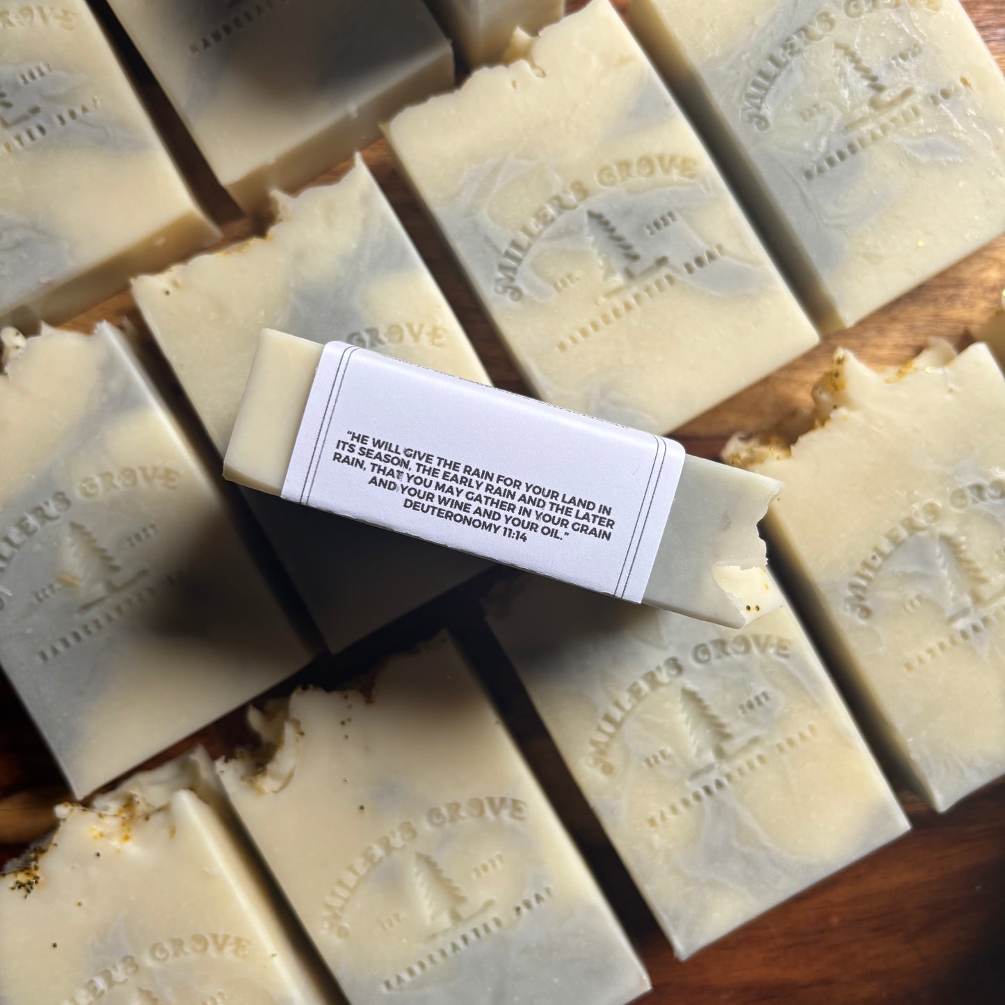 Bar of soap with Miller's Grove label surrounded by multiple bars of soap on a wooden surface