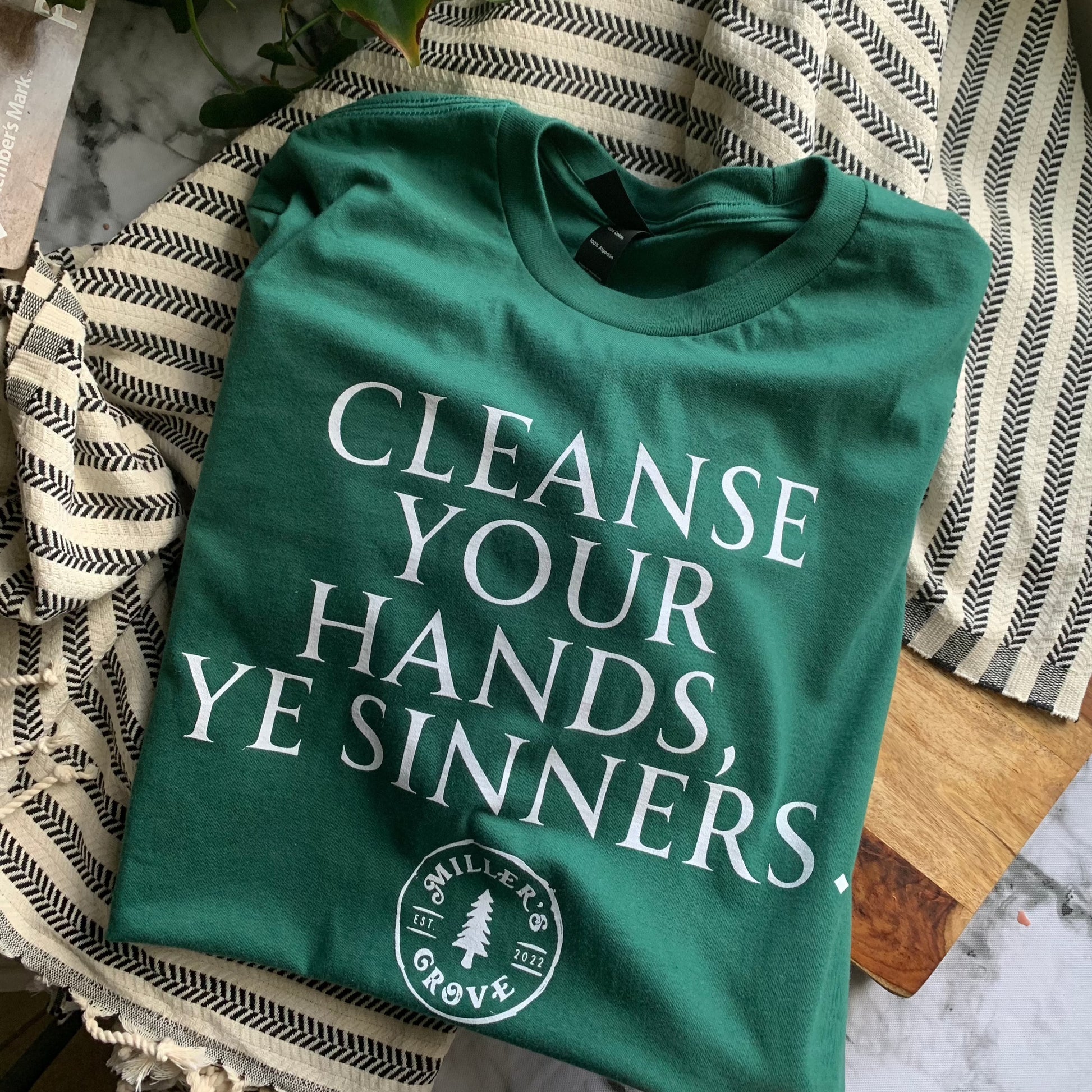 Green short sleeve t shirt that says "cleanse your hands, ye sinners" on the front