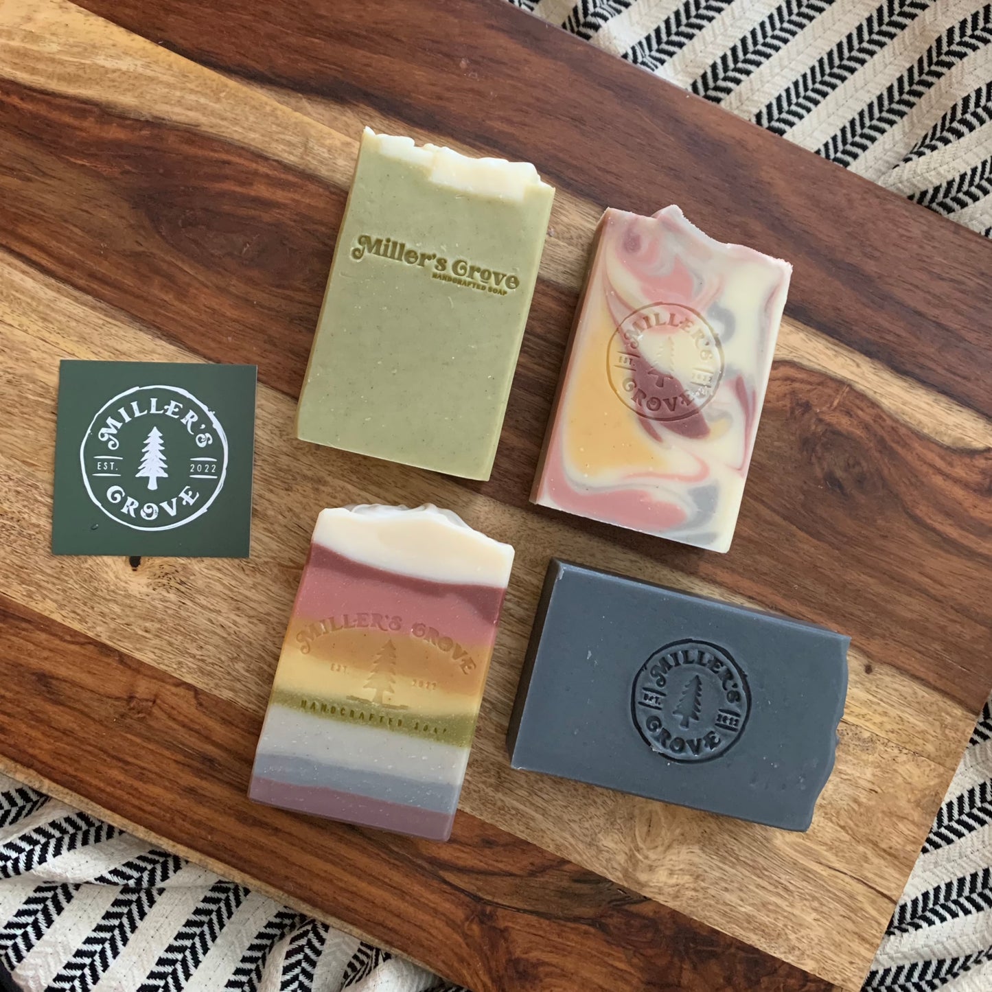Four bars of soap (one green bar, one rainbow bar, one black bar and one swirly multi colored bar)