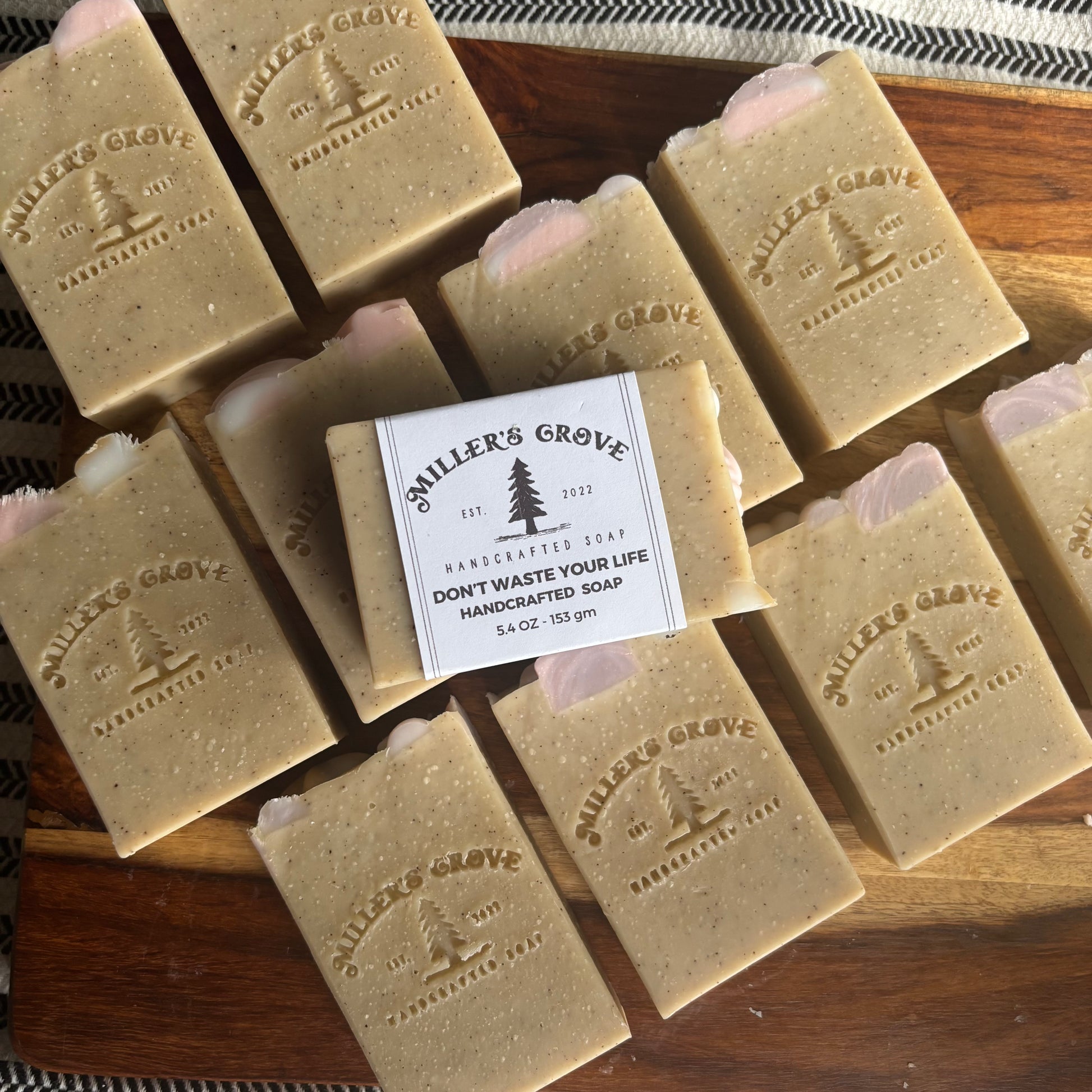 Multiple bars of 'Miller's Grove' soap on a wooden surface with a central bar featuring the brand label.