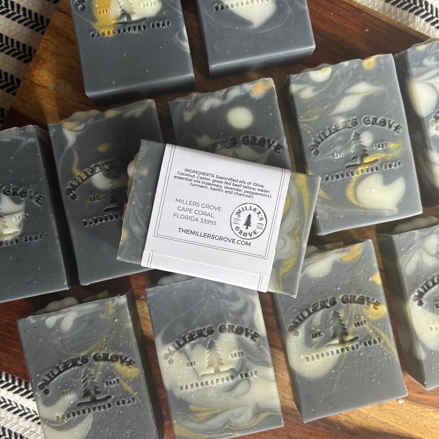 Multiple bars of Millers Grove soap on a wooden surface with a label in the center.