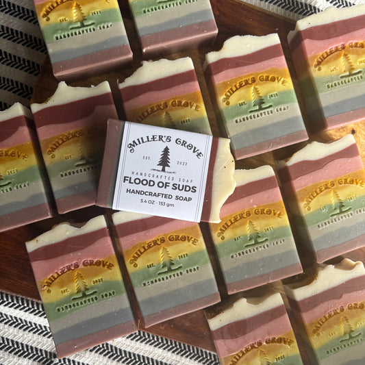 Handcrafted soap bars with colorful stripes and a label for 'Miller's Grove' on a striped fabric background.