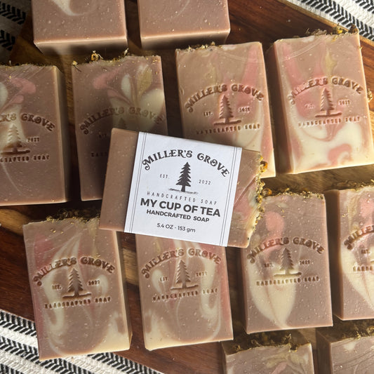 Handcrafted soap bars with 'Miller's Grove' branding on a wooden tray.