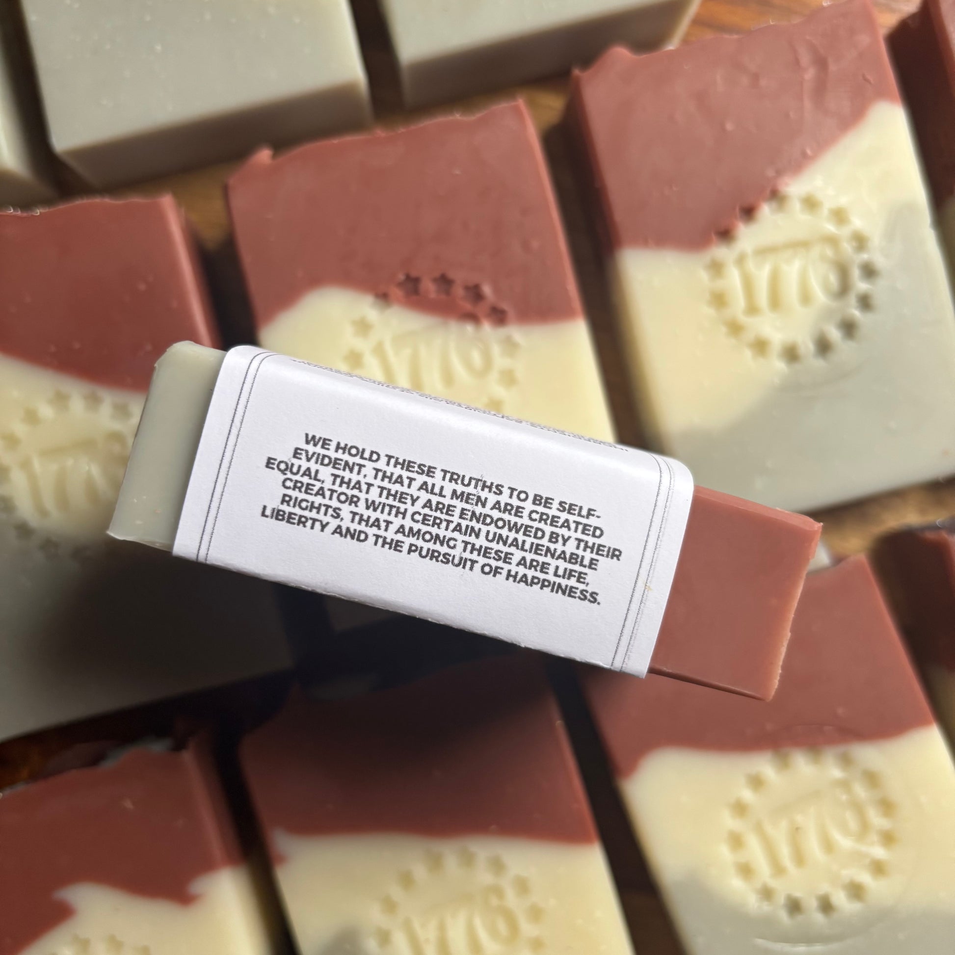 Soap bars with a visible label featuring text, arranged on a wooden surface.