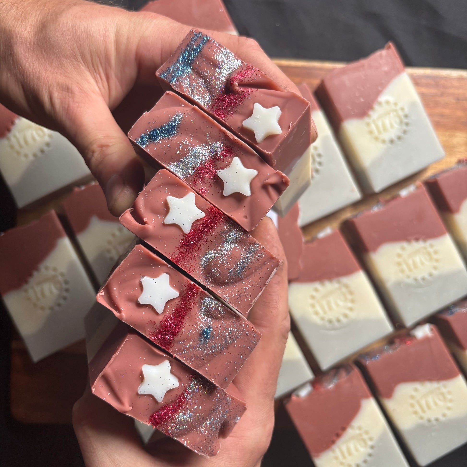 Hand holding a stack of star-shaped soap bars with a wooden background