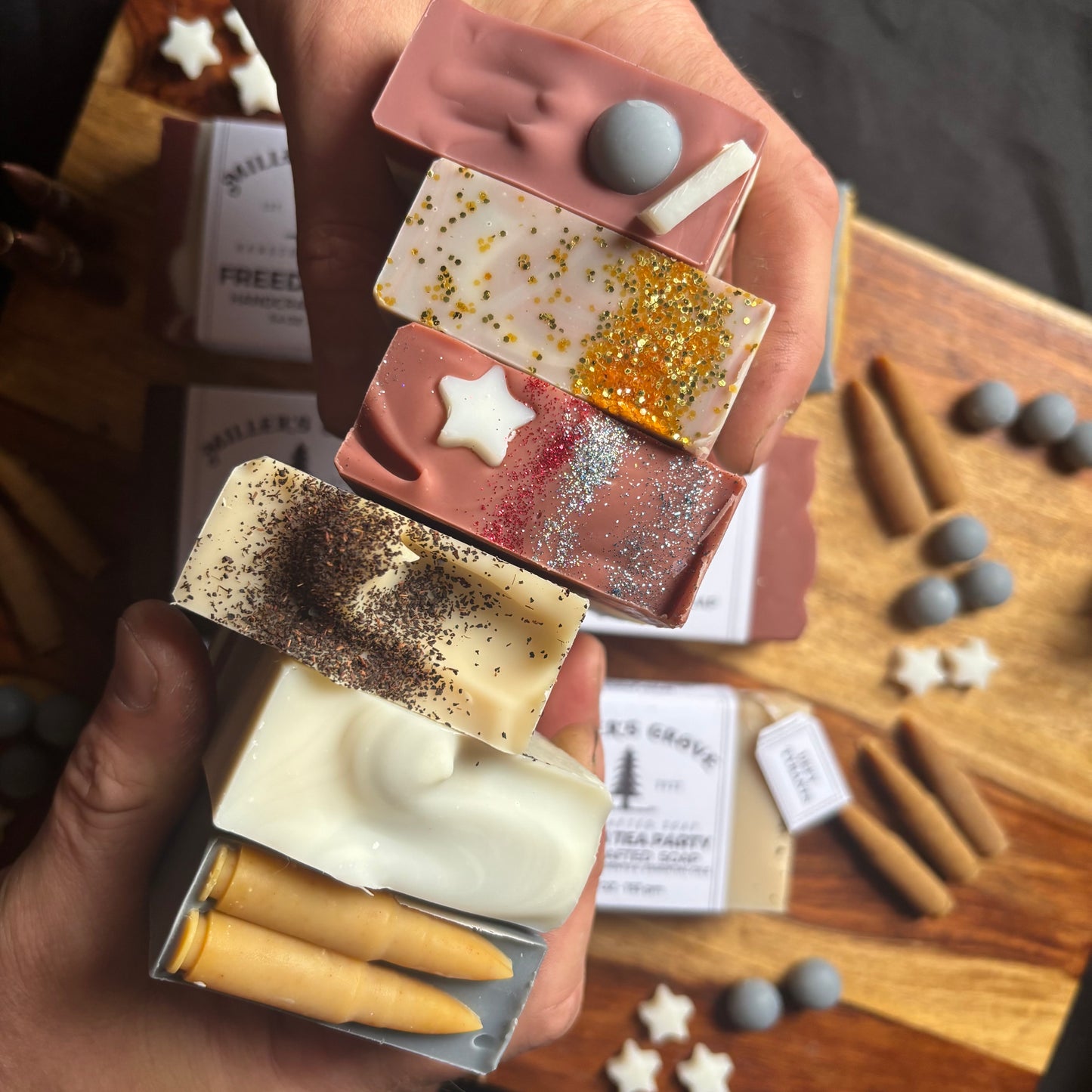 Hand holding a box of colorful soap bars with a wooden background